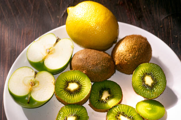 Whole and sliced tropical fruits; pineapple, nectarines, apples, pears and kiwi fruit in the air isolated on white background
