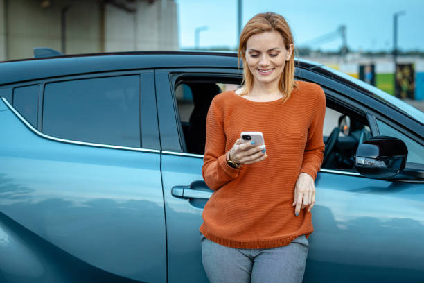 istock Female driver using smart phone by her car in the city 2167615980