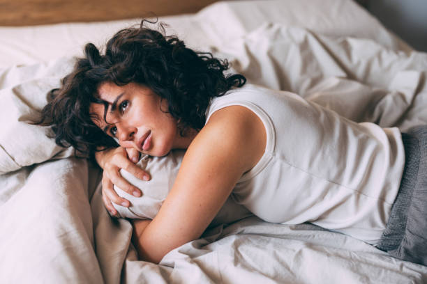 istock Woman Relaxing Comfortably On Bed With Thoughtful Expression 2167617406