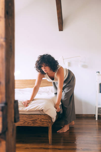 istock Woman Making Bed in Cozy Sunlit Bedroom 2167617417
