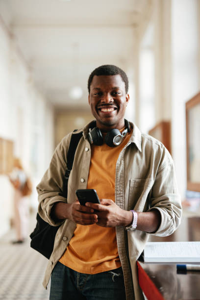 istock Happy University Student Standing in Hallway with Mobile Phone 2167617593
