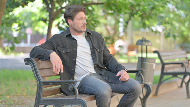 istock Middle Aged Man Sitting Outdoor on Bench 2167618840