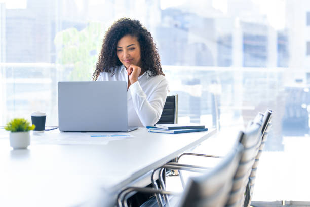 istock Young woman working on a laptop computer in the office. She is sitting at a conference table in a meeting room. 2167622561