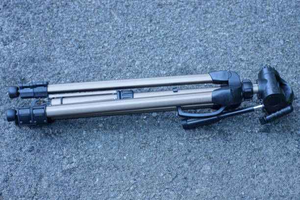 one big brown black camera tripod lies on gray asphalt on the street