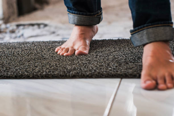 Close up feat on a mat at the home as a man is seen entering through the front Close up feat on a mat at the home as a man is seen entering through the front. Welcome mat, interior home. key doormat stock pictures, royalty-free photos & images