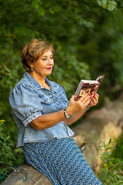 istock Woman reading a book while sitting on a log in a lush green forest 2167632885