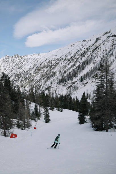 Female skier enjoys the beautiful scenics of the French Alps, going downhill on a beautiful empty slope.