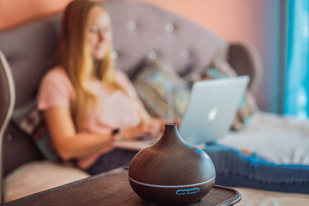 istock A woman sits on a bed and works on a laptop. Aroma diffuser next to the bed 2167644425