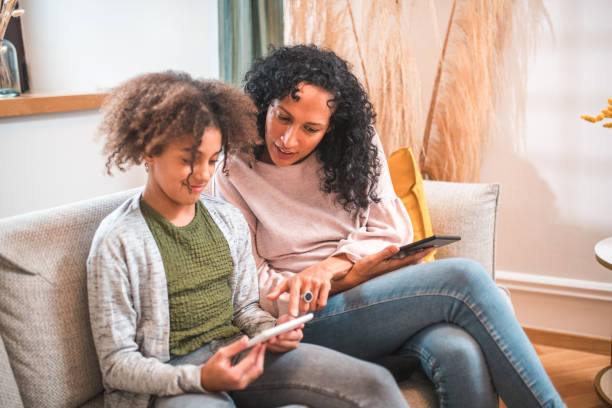 istock Hispanic Mother and Mixed Race Daughter Reading E-Books 2167645138