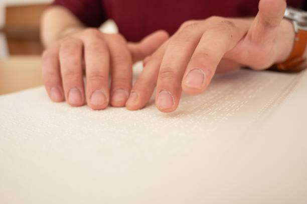 istock Visually impaired man reading a braille book. 2167661339