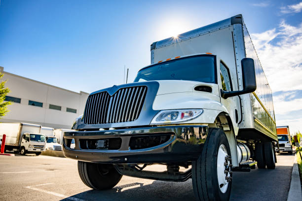 Compact middle duty rig semi truck with long box trailer standing on the wide warehouse parking lot with another trucks stock photo