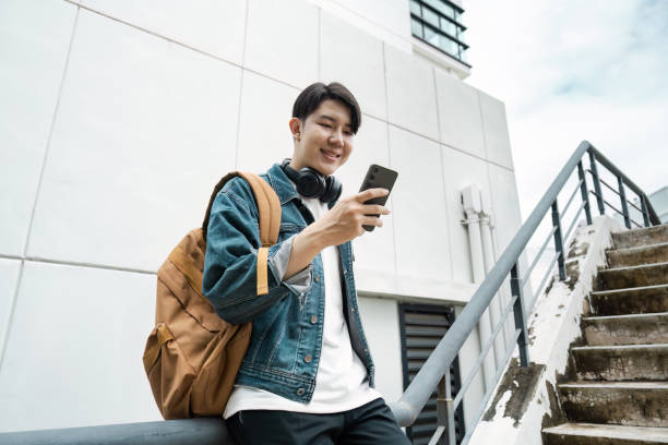 istock Young Traveler Using Smartphone While Exploring Urban Cityscape with Backpack and Headphones 2167668282
