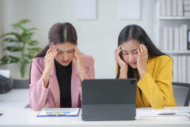 istock Two businesswomen suffering from headache working in office 2167681412