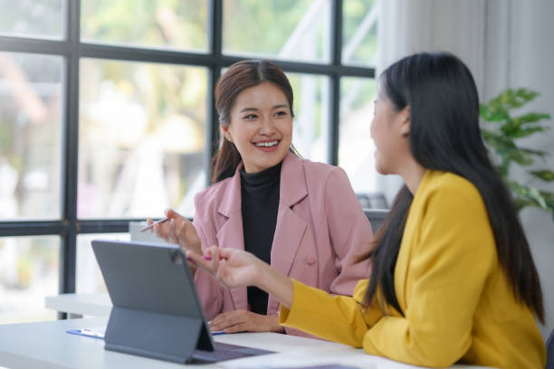 istock Two young businesswomen collaborating and discussing a project on a tablet in a modern office 2167681419