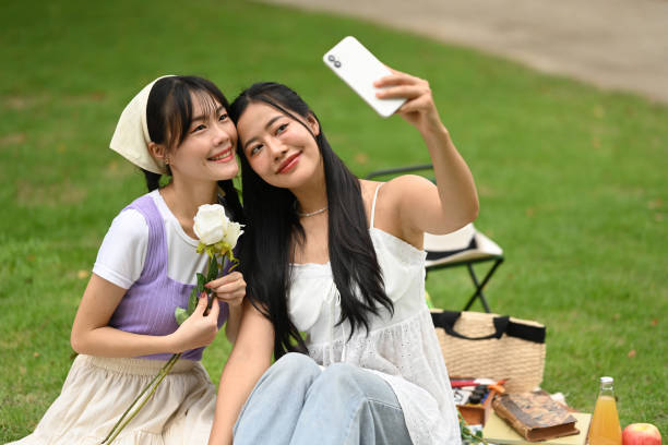 istock Affectionate lesbian couple taking selfie with smartphone during picnic in the park 2167688499