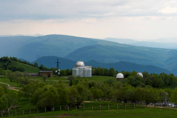 Observatory domes in a green valley with hills and cloudy sky. Special astrophysical observatory of the Russian academy of sciences, Arkhyz