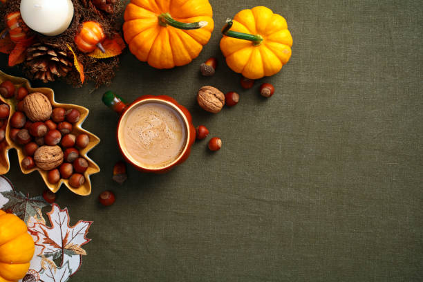 istock Flatlay composition with pumpkins, coffee cup, nuts, acorns, candle on green textile desk table. Hygge style, cozy autumn holiday concept. Flat lay, top view, overhead. 2167704024