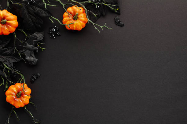 istock Spooky Halloween flat lay with pumpkins, maple leaves, branches with bats on black background. 2167705251