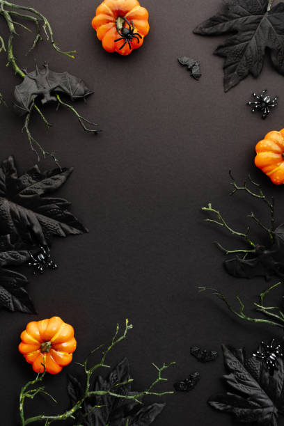 istock Top view scary Halloween background with pumpkins, maple leaves, bats on branches on dark table. 2167705336