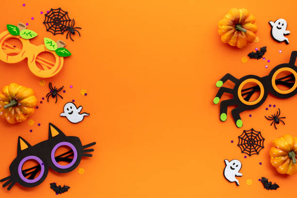 istock Flat lay composition with Halloween party decorations, kids eyeglasses, pumpkins, spiders, bats on orange background. 2167705626