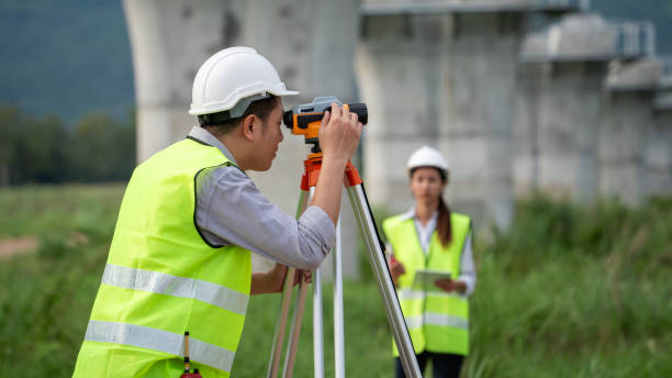 istock Survey team is working with a theodolite and road construction plans. Civil engineers are taking measurements with surveying tools during the construction. 2167708899