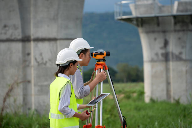 istock Survey team is working with a theodolite and road construction plans. Civil engineers are taking measurements with surveying tools during the construction. 2167709455