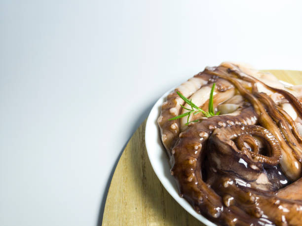 istock Fresh octopus on a white plate ready for cooking. Seafood on white background 2167721372