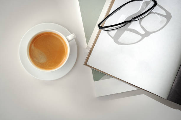 istock A Cup of Coffee, Glasses, and a Stack of Magazines on a White Tabletop 2167726376