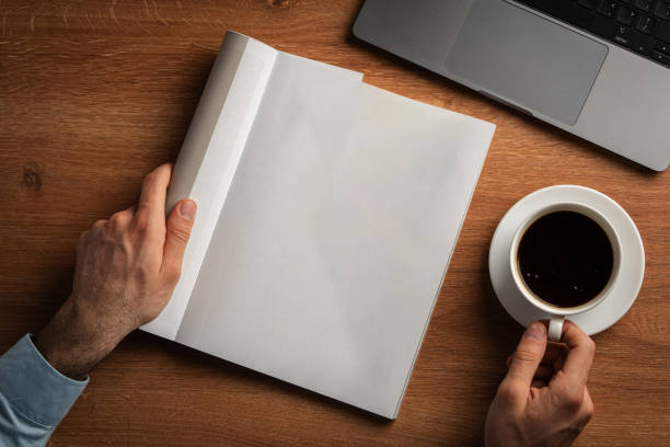 istock Man Reading Page of Magazine While Holding Coffee Cup 2167727378