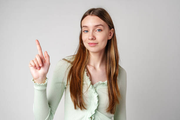 istock Young Woman Pointing Upwards With a Smile 2167729110