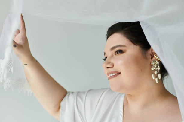 istock Stunning plus-size bride shines in elegant gown and accessories on a neutral backdrop 2167744092