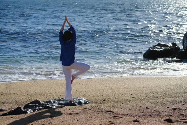 istock Woman practicing yoga on the beach at sunset 2167746337