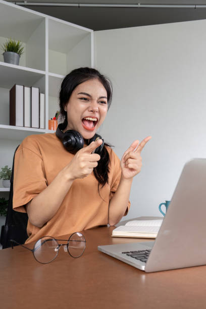 istock Young Woman Celebrates Passing Exam with Joyful Expression in Modern Home Office Setting 2167746493