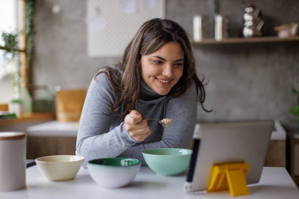 istock Young woman eating breakfast and using a tablet 2167752728