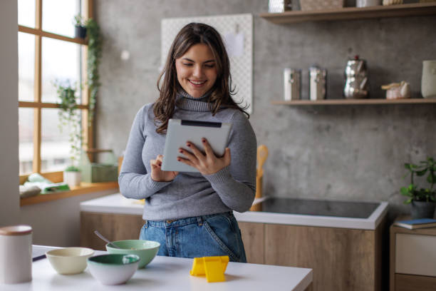 istock Young woman making herself breakfast and using a tablet 2167752735