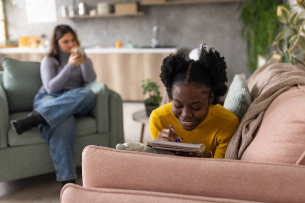 istock Young woman writing in a notebook at home 2167753422