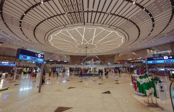 Jeddah, Saudi Arabia - April 29, 2024: The bustling interior of Jeddah Airport Terminal features a spacious layout with contemporary lighting, check-in counters, and travelers preparing for their journeys.