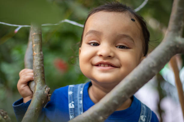 istock innocent toddler holding tree branch with cute facial expression at day from flat angle 2167759667