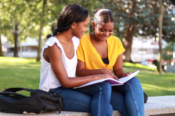 istock Two Hispanic female students sitting on a park bench, deeply engaged in their studies 2167761591