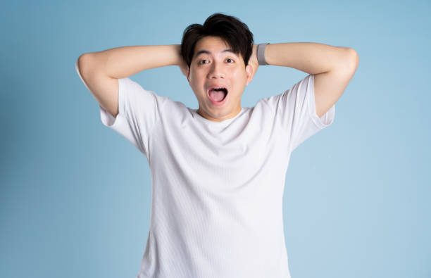 istock Portrait of Asian guy posing on blue background 2167764471
