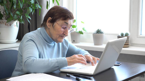 istock Elderly Woman in Glasses Working on Computer at Home 2167764852