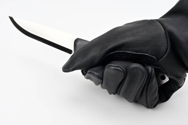 A hand holding a knife taken from a knife block and the thumb pressing on the blade to test its sharpness. It's not the sharpest knife in the block.