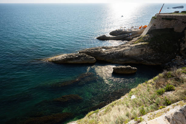 Sunlit coastal landscape with tranquil sea and rugged cliffs ideal for relaxation in Ulcinj, Montenegro. Captured at a serene sea vista with a rocky shoreline, this image embodies calmness and natural beauty.