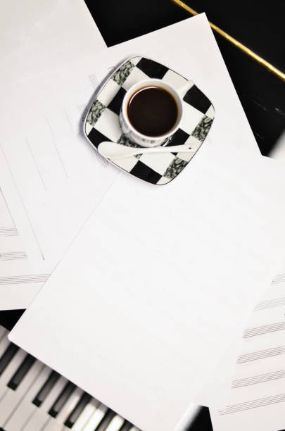 A cup of black coffee with music sheets on a piano