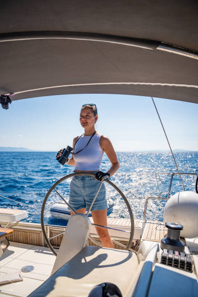 istock Young female captain on the yacht looking through binoculars during sailing boat control. Travel and active life. Yachting 2167776309