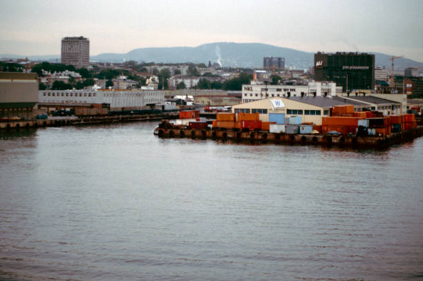 Oslo, Norway, 7 August 1986. The ship arriving in Oslo, overcast skies and a bit of fog. Lots of containers, a few cars and port buildings. In the distance the city with some skyscrapers. Advertising signs and company names on some buildings