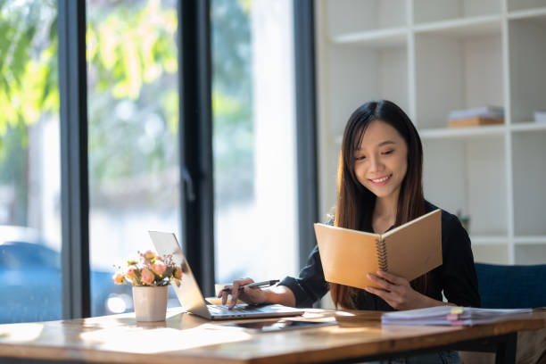 istock Attentive businesswoman jotting down notes while working on a project with her laptop at a sunny table. 2167777569
