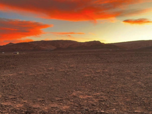 This striking image captures the silhouette the horizon in the distance in Australia’s Red Centre at twilight. The sky glows with a smooth gradient of warm yellows and cool purples
