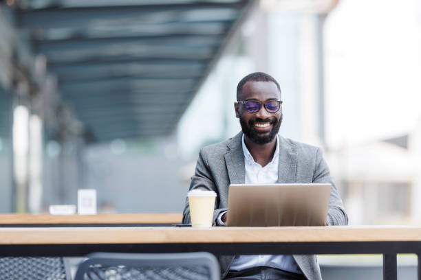 Smiling businessman using laptop at outdoor cafe