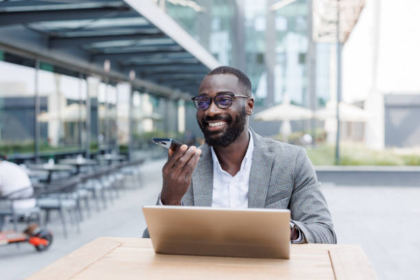 istock African American man working remotely outdoors and recording a voice message 2167779424
